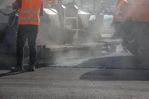 Men working with asphalting paver machine during road street repairing works at 库存照片