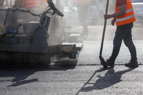 Men working with asphalting paver machine during road street repairing works at Stock Photos