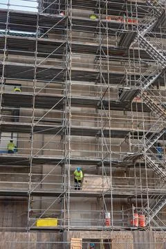Men working on a large multi- level scaffolding in front of a tall building Stock Photos