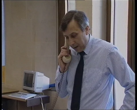 Men working in office while people prepare broadcasting room, UK 1990 Stock Footage 147438145