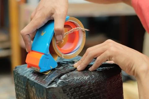 Men wrapping a package using cardboard, bubble wrap, and duct tape. Goods d.. Stock Photos