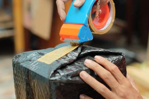Men wrapping a package using cardboard, bubble wrap, and duct tape. Goods d.. Stock Photos