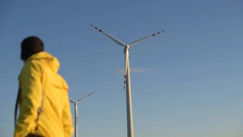 Men in yellow clothes blurred on the background of wind turbines in focus Stock Footage 201115880