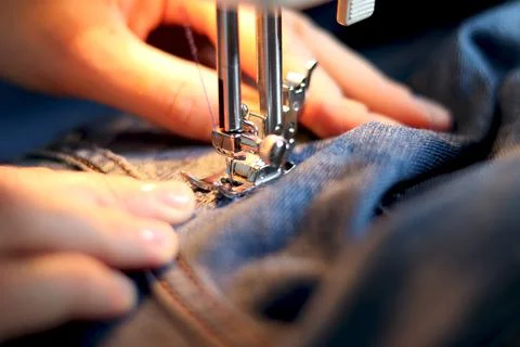 Mend jeans on a sewing machine. Patch torn jeans with a sewing machine. The c Stock Photos