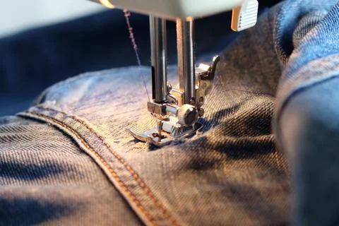 Mend jeans on a sewing machine. Patch torn jeans with a sewing machine. The c Stock Photos