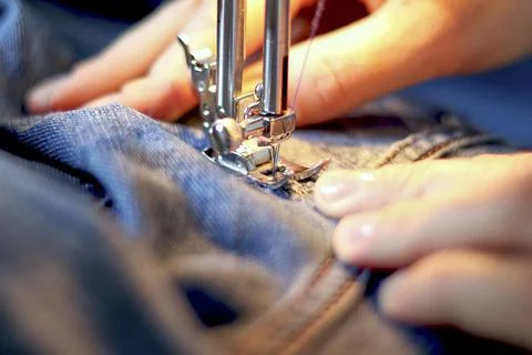 Mend jeans on a sewing machine. Patch torn jeans with a sewing m Stock Photos