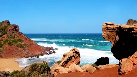 Menorca, red rock formation at Cala Pilar and vivid blue sea Stock Footage 73608295