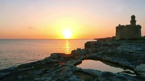 Menorca, San Nicolas tower during sunset and puddle in foreground, Ciutadella Stock Footage 73608269