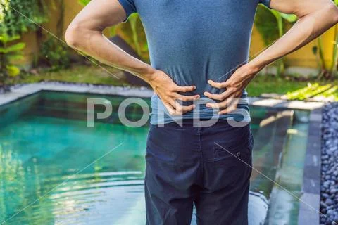 Men's back hurts against the backdrop of the pool. Pool helps with back pain Stock Photos