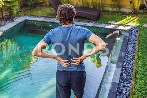 Men's back hurts against the backdrop of the pool. Pool helps with back pain Stock Photos