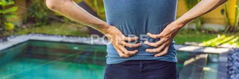 Men's back hurts against the backdrop of the pool. Pool helps with back pain Stock Photos