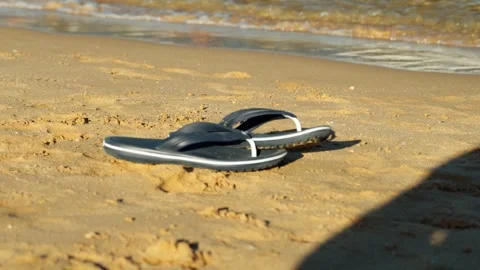 Men's flip-flops on a sandy beach by the sea. 스톡 동영상 330062037