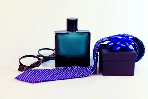 Mens gift concept featuring cologne, eyeglasses, necktie and gift box Stock Photos