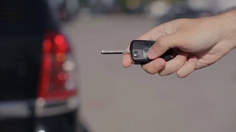 Men's hand pressed on the remote control car alarm and blinking lights Stock Footage