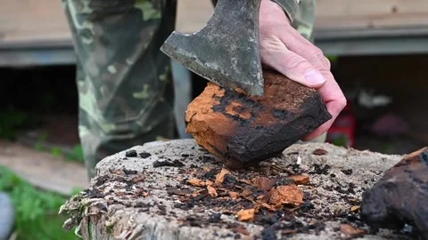 Men's hands with an axe clean chaga mushroom birch fungus in the fresh air Stock Footage 134621049
