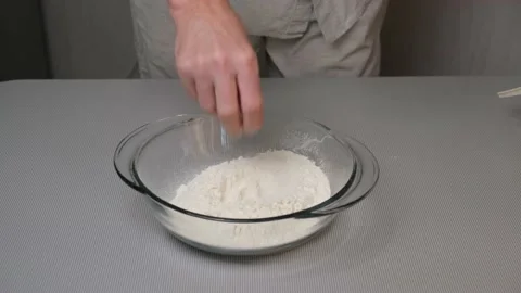 Men's hands break an egg with a knife into sifted flour in a glass bowl. Stock Footage 166035873