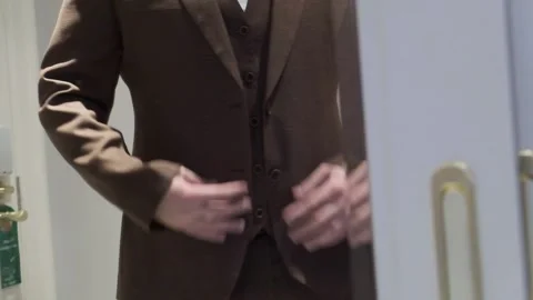 Men's hands buttoning a brown jacket Stock Footage 141359410