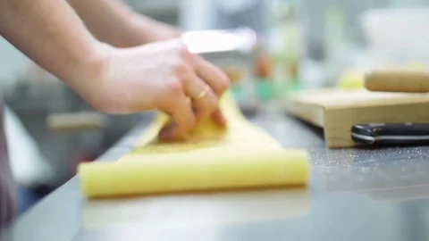 Men's hands chef lay out on the table a thin layer of dough. Man use a rolling Stock Footage 74718593