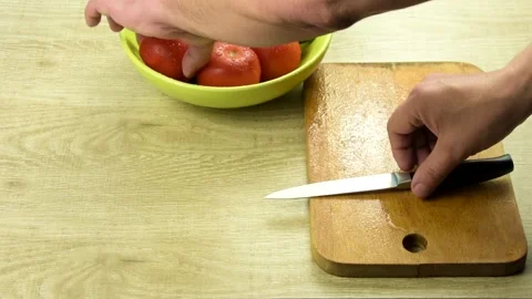 Men's hands close-up. Cut tomatoes and cucumbers on a wooden cutting board. Stock Footage 130873771