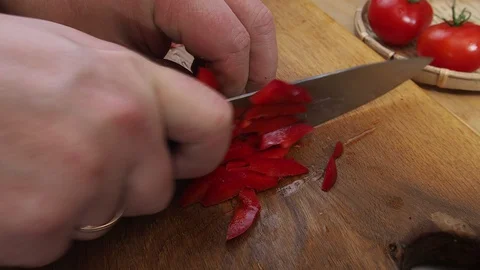 Men's hands close up cutting bell peppers on a cutting Board made of wood Stock Footage 129807401