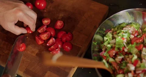 Men's hands cut red cherry tomatoes with a knife on a wooden board, sliced Stock Footage 345756918