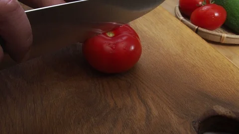 Men's hands cut a tomato in half with a knife Stock Footage 129807625
