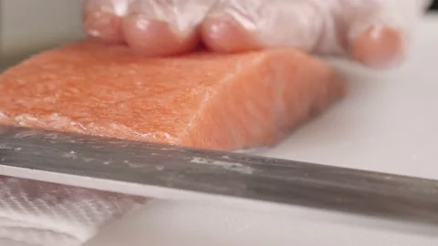 Men's hands cut off the top layer from the red fish for making rolls.Cooking sal Stock Footage 163946969