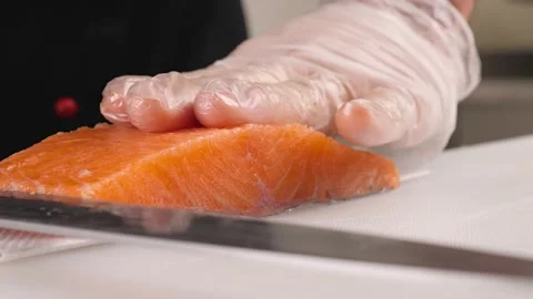 Men's hands cut off the top layer from the red fish for making rolls.Cooking sal Stock Footage 163946984