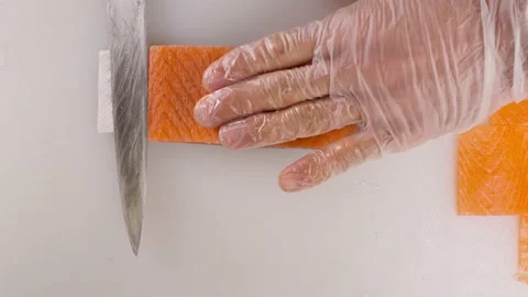 Men's hands cut off the top layer from the red fish for making rolls.Cooking sal Stock Footage 163947073