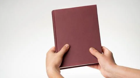 Men's hands hold a book or notebook in a burgundy binding on a white background Stock Photos