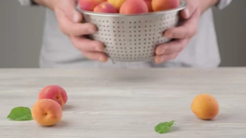 Men's hands hold a colander full of garden apricot Stock Footage 136101662