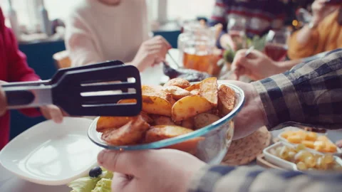 Men's hands hold out cup of baked potatoes from which grandfather tongs potatoes Stock Footage 143486653