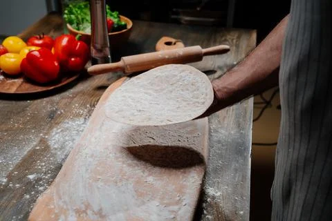 Men's hands hold a thin flatbread. Cooking pizza, noodles or pitta at home Stock Photos