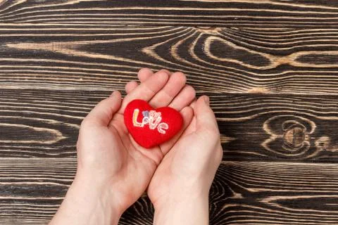 Men's hands holding red heart over wooden background Stock Photos