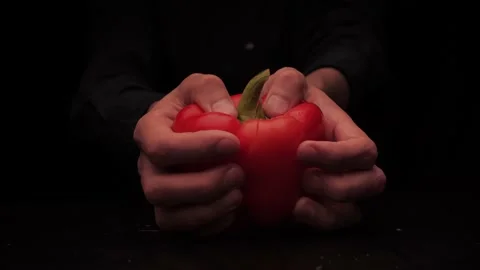 Men's hands offer to hold two pieces of red bell pepper on a dark background Stock-Footage 142863189