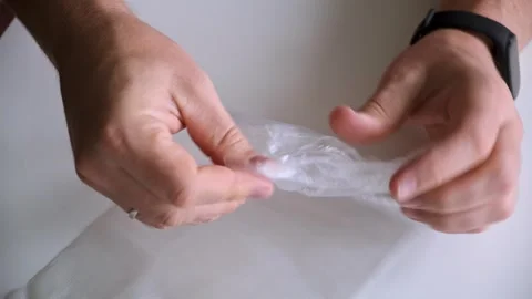 Mens hands open a new disposable cellophane bag. Rustling sounds. Small plastic Stock Footage 323801438