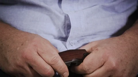 Men's hands open a small folding pocket knife and playing with a blade Vidéo 100882656