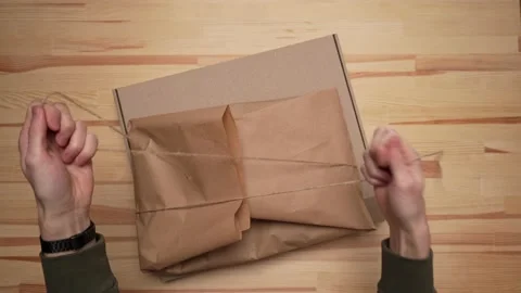 Men's hands pack the package in paper and place it in a paper box Stock Footage 232875631