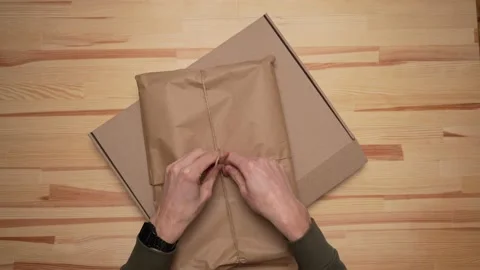 Men's hands pack the package in paper and place it in a paper box Video stock 232875632