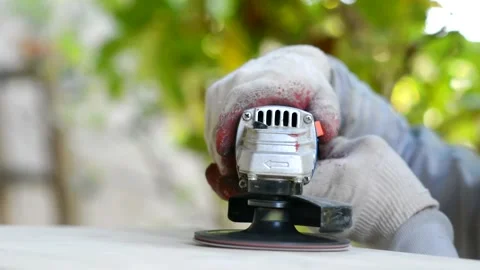 Men's hands in protective gloves hold an angle grinder and grind Stock Footage 163302087