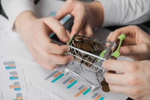 Men's hands pulled in different directions Dummy shopping cart filled with coins Foto stock