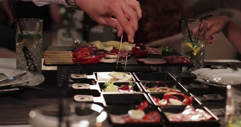Men's hands put champignons and lettuce leaves in a tray with raclettes. Stock Footage 179026010