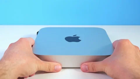 Men's hands put a new mac mini on the computer table. Close-up of the hands of a Stock Footage