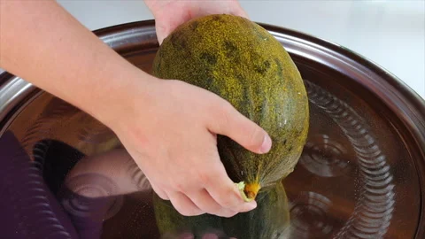 Men's hands put some fresh and juicy melon on a large dish Stock Footage 220789921