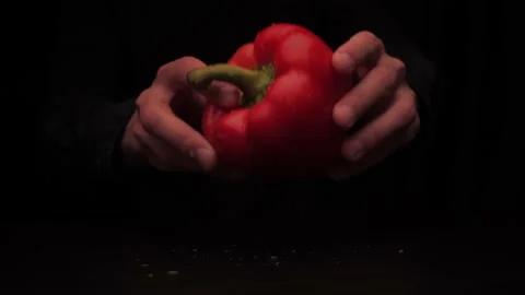Men's hands put on the table red colored bell pepper on a dark background Stock Footage 144370529