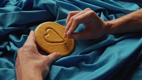 Men's hands scratch brown sugar candy with metal needle pattern in form of heart Stock Footage 162227759