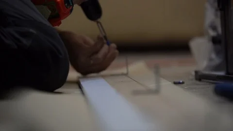 Men's hands screw/ attach the iron / metal corner to the wooden Board with a scr 動画素材 104028161