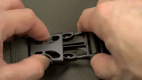 Men's hands snap and unbutton the Fastex on the green fabric of the backpack. Video stock 151020833