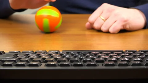 Men's hands spin a small ball next to the keyboard Stock Footage 99861359