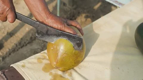 Men's hands split a coconut with a machete Fotos de archivo